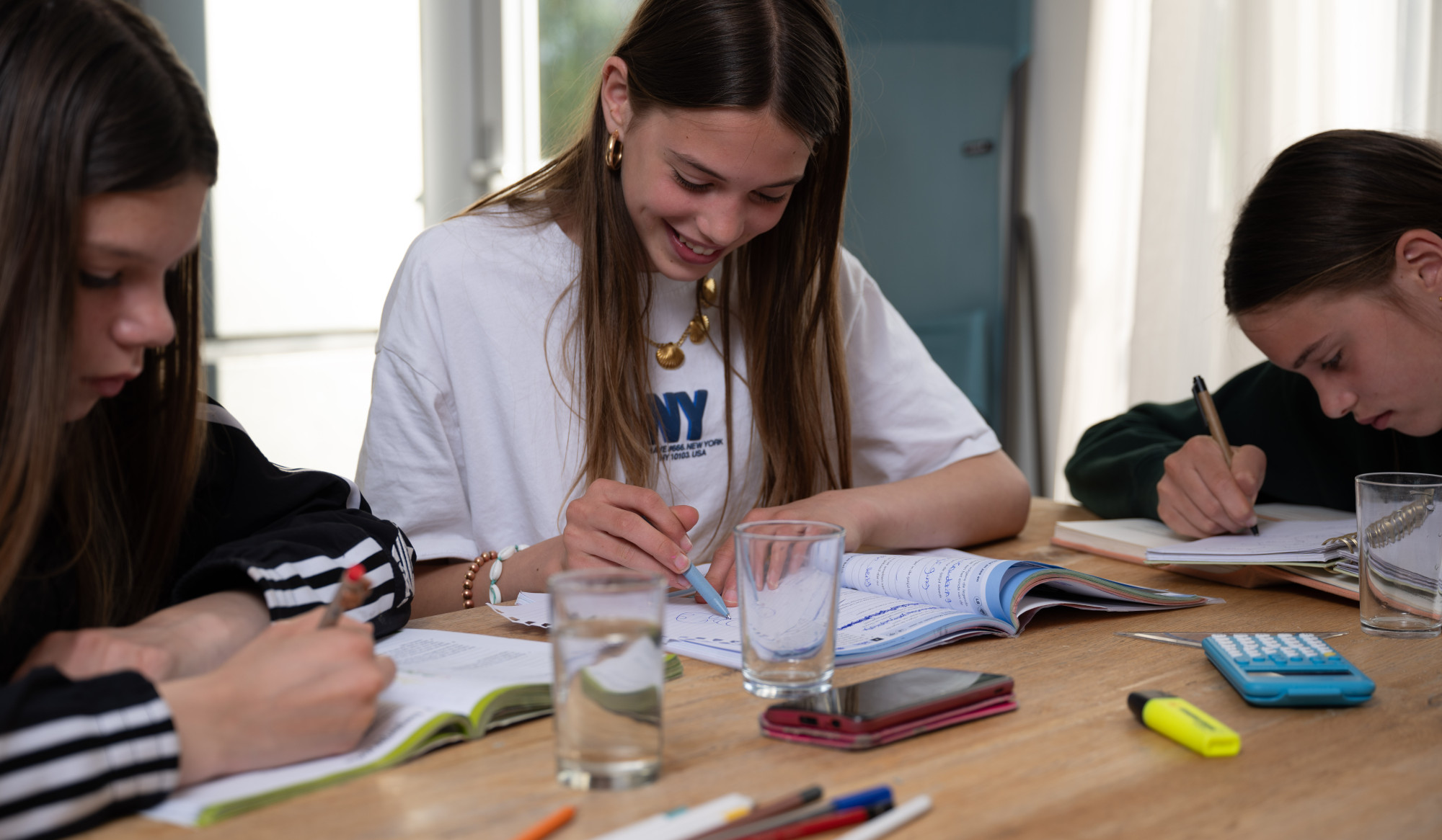 Drie jongeren maken huiswerk aan de keukentafel